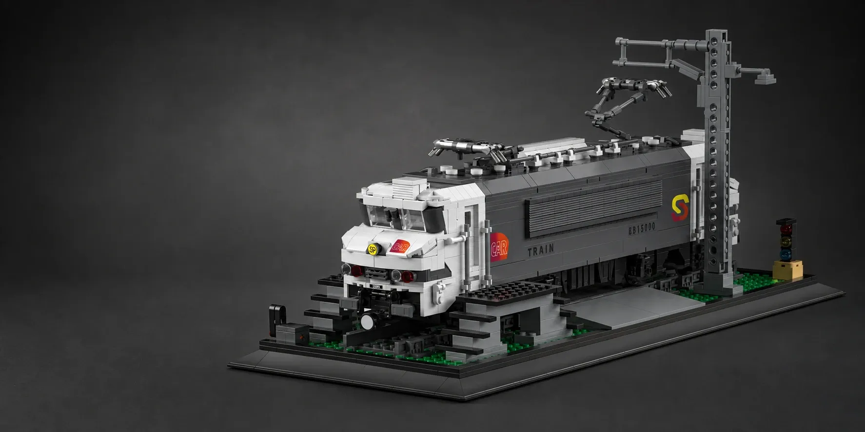 A detailed grey and white brick-built electric locomotive displayed on a black presentation base with overhead rail lines and a signal, shown in a studio-style product shot.